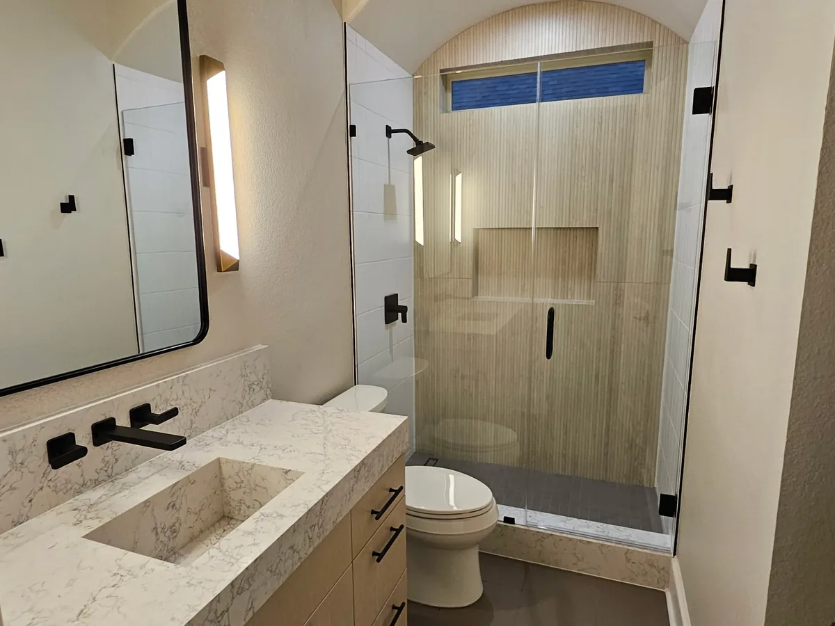 Glass shower enclosure with arched tile niche