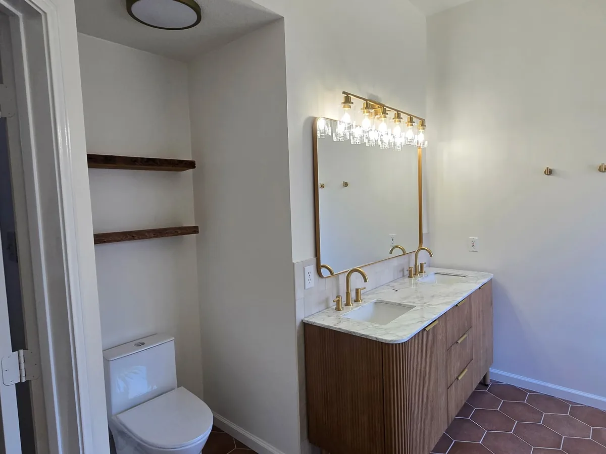 Wood vanity with gold fixtures and open wall shelves