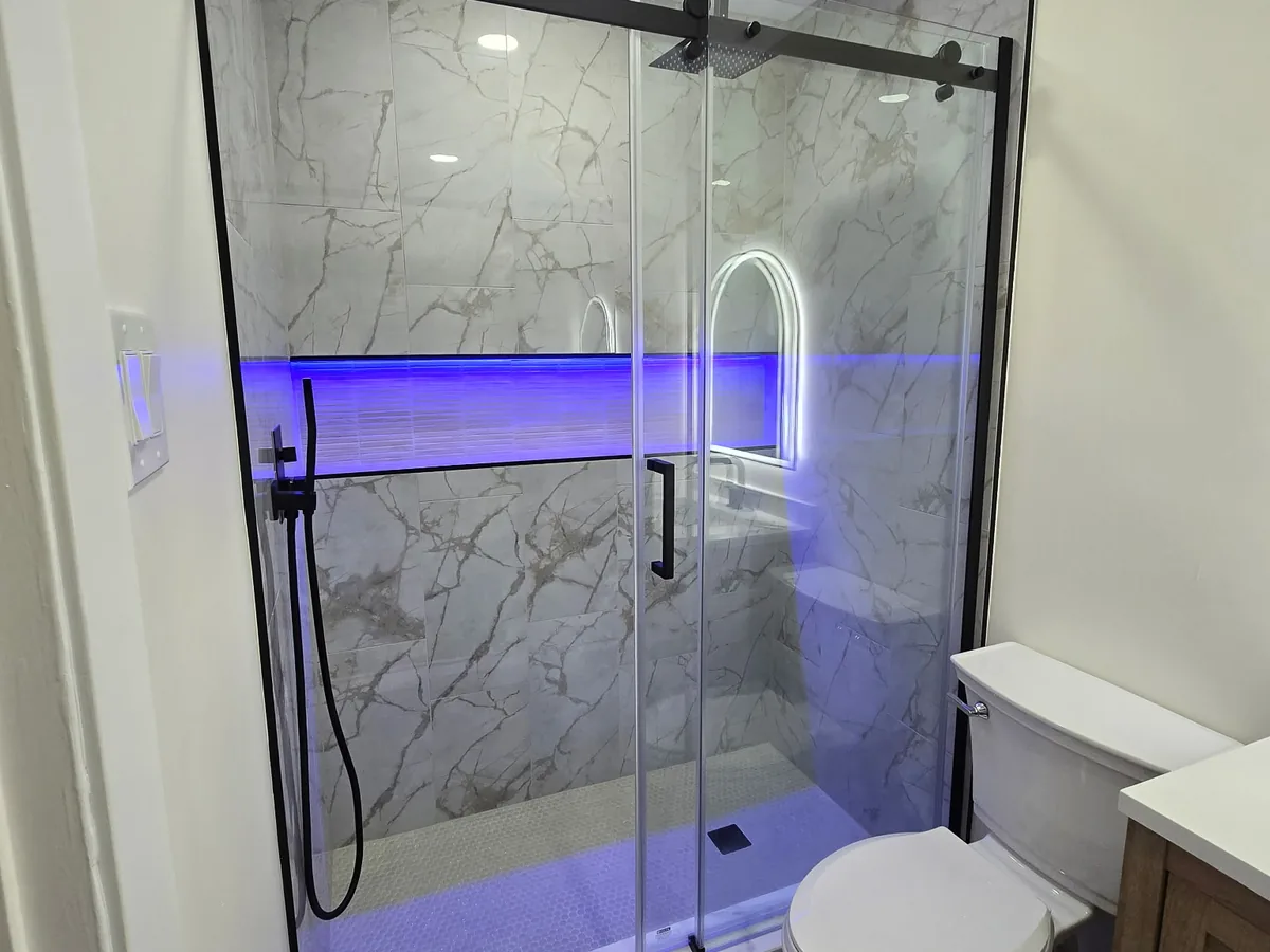 Marble tile shower with black sliding glass door